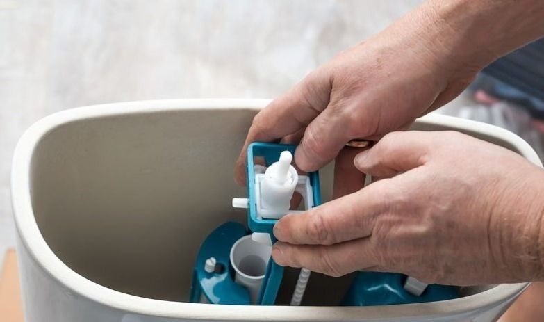 Plumber replacing the water pump in a toilet.