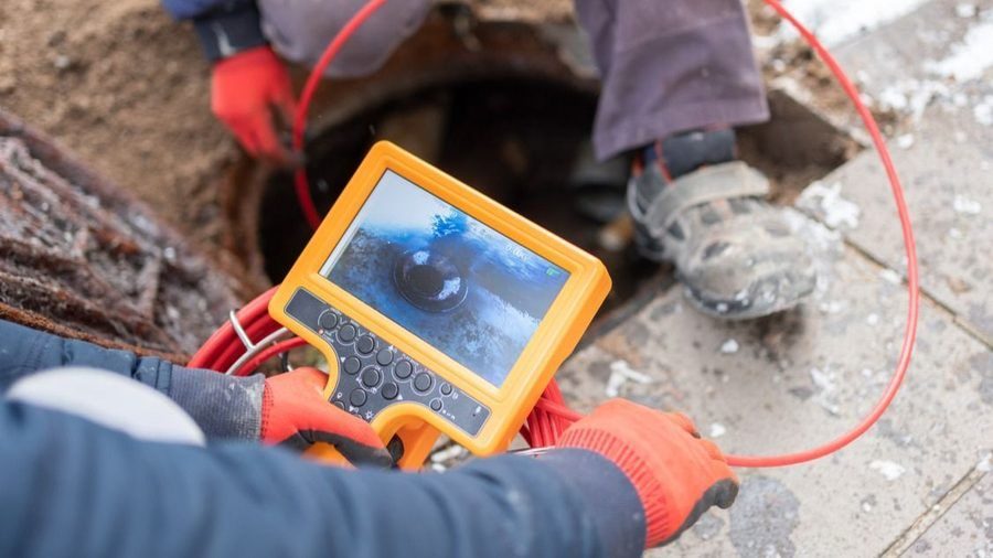Two plumbers inspecting a plumbing system with a camera to determine next steps.
